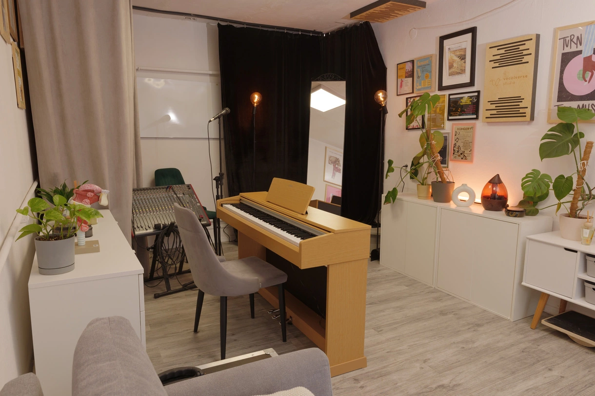 Sala duża Vocalverse Studio, pianino, mikrofony, lustro, nagłośnienie, obrazki na ścianie, komoda.